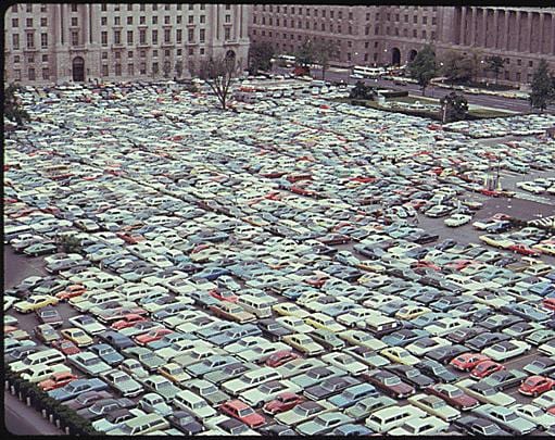 Parking lot in what is now the Reagan Building. Commerce Department in background on right. (1974)