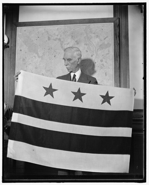D.C. Commissioner, Melvin Hazen, who chose the design, is pictured with the new flag October 17th, 1938 (Library of Congress)