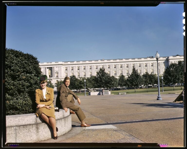 1943. On maneuvers in wartime Washington. "A soldier and a woman in a park, with the Old [Russell] Senate Office Building behind them." 4x5 Kodachrome transparency, photographer unknown. Office of War Information.