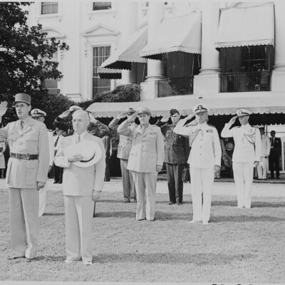 Photograph of President Truman and French President Charles de Gaulle, during welcoming ceremonies on the White House lawn, with officers saluting in the background. (August 22nd, 1945)