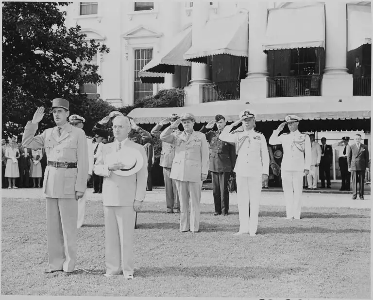 Photograph of President Truman and French President Charles de Gaulle, during welcoming ceremonies on the White House lawn, with officers saluting in the background. (August 22nd, 1945)