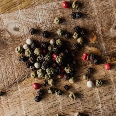 mix of pepper seeds on wooden surface