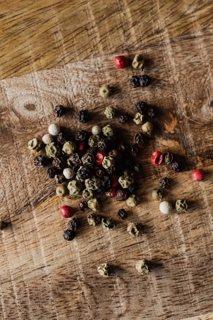 mix of pepper seeds on wooden surface