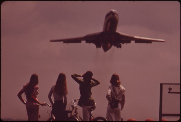One Of The Bicyclists Holds Her Ears Against The Roar Of The Jet, Taking Off From National Airport, May 1973