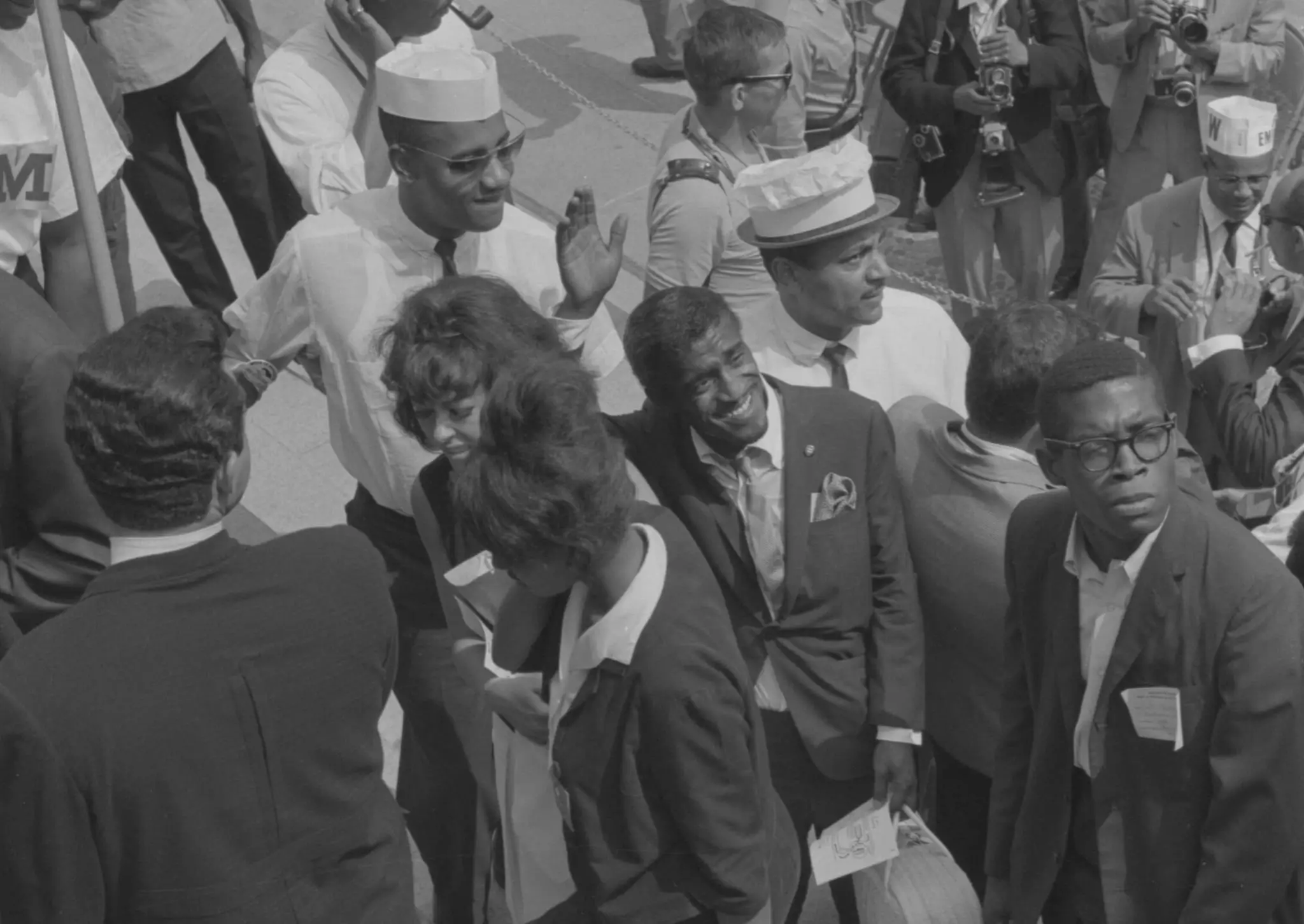 Sammy Davis, Jr., waving to people as he walks past marshals at the Lincoln Memorial during the March on Washington, 1963