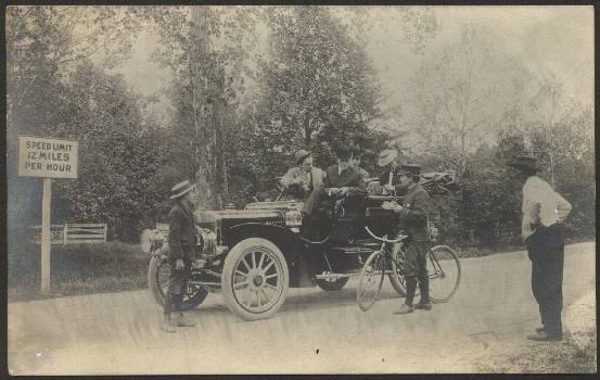 Town Marshall, Charles Collins, ticketing a car along Conduit Road (MacArthur Boulevard). Note the 12MPH limit. ca. 1907