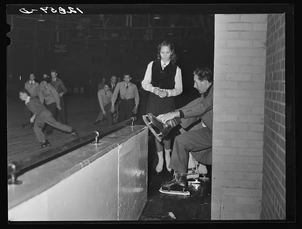 Chevy Chase Ice Palace, Washington. D.C. Skater fastening on skates while companion watches