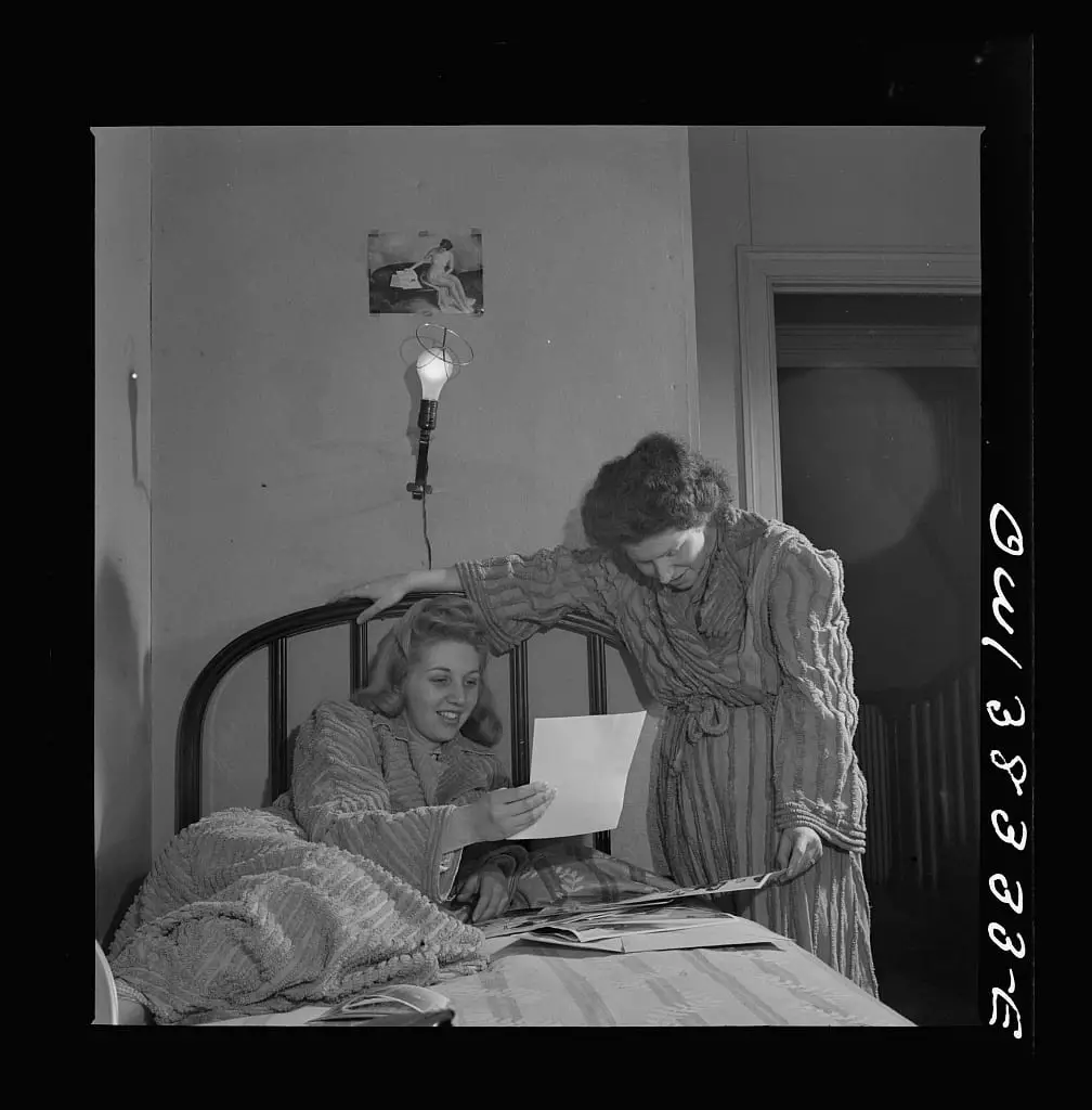 Two girls looking at pictures in their room in a boardinghouse