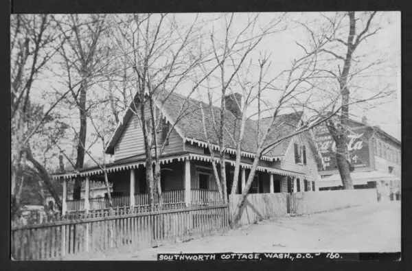 View of the east and south elevations of Mrs. E. D. E. N (Emma Dorothy Eliza Nevitte) Southworth's cottage, located at the southwest corner of Prospect and 36th Streets NW. In background can be seen 1224 36th Street NW whose Prospect Street elevation is painted with "Drink Coca-Cola."