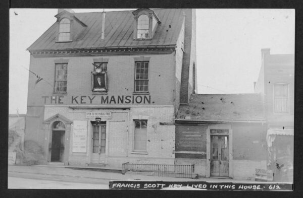 View of the M Street NW elevation of the two-story Key Mansion with Key's single-story law office attached to west side of structure. A portion of the commercial building continuing west along the street is also visible.