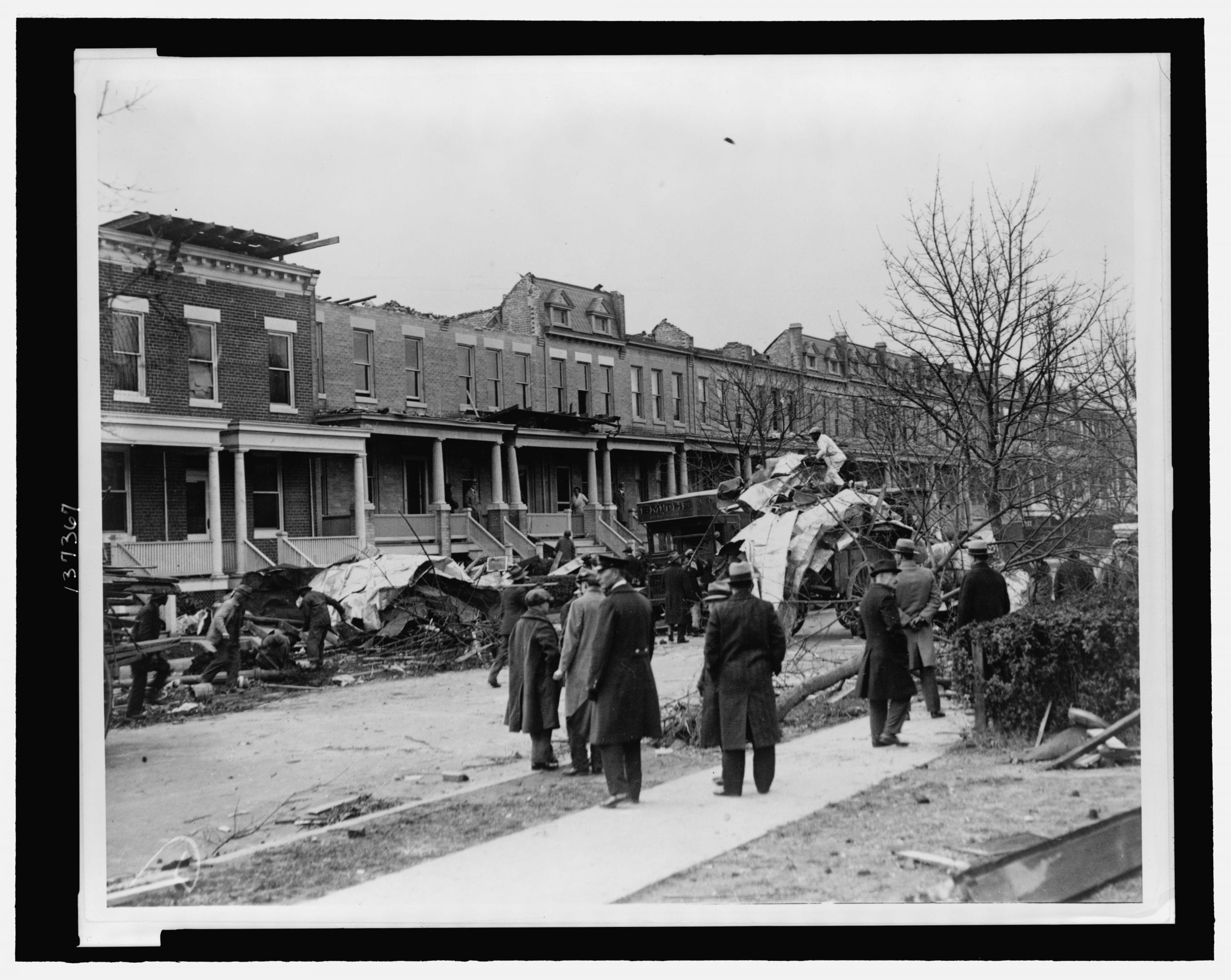 Men watching debris being cleaned up at row houses on A St., NE, near 14th St., severely damaged by a tornado on Nov. 17, 1927