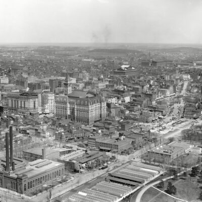Circa 1911. "Washington from Washington Monument." Points of interest in this panoramic view include B Street (today's Constitution Avenue), running diagonally from the Potomac Electric powerhouse at lower left; Louisiana Avenue, branching off in the general direction of Union Station at upper right; the Old Post Office and its clock tower at left-center across Pennsylvania Avenue from the Raleigh Hotel under construction; the Agriculture Department greenhouses in the foreground with a corner of the Smithsonian "National Museum" at far right, just below Center Market; Liberty Market at upper left, below what looks to be a vast tent encampment; and, at right-upper-center, the Pension Office north of Judiciary Square and the District Court House. 8x10 glass negative, Detroit Publishing Co.