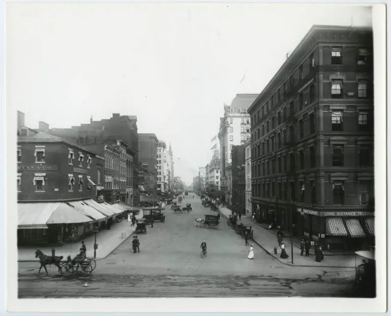 View of 15th & F Streets, NW looking east with horse carriages and a bicyclist pictured.