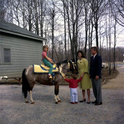 31 March 1963 President John F. Kennedy and family watch Caroline Kennedy riding a horse named "Tex" at Camp David. "Tex" is wearing a blue and gold Moroccan saddle, a gift to President Kennedy from King Hassan II. Photograph includes: (L-R) Caroline Kennedy, John F. Kennedy, Jr., First Lady Jacqueline Kennedy, and President Kennedy. Camp David, Maryland. Please credit "Robert Knudsen, White House/John F. Kennedy Presidential Library and Museum, Boston"