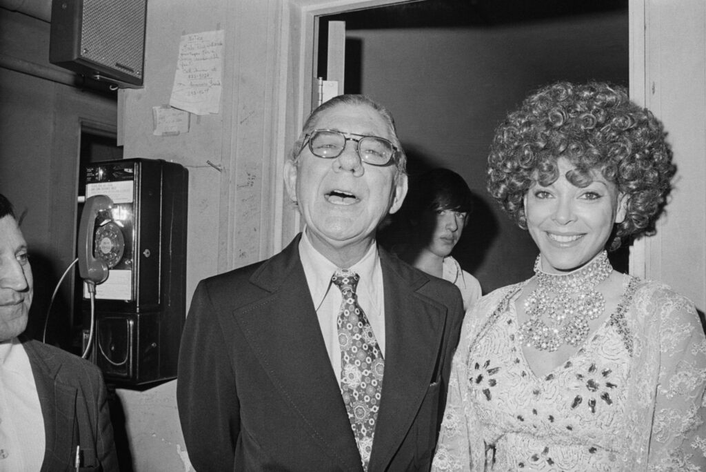 Congressman Wilbur Mills and exotic dancer Fanne Foxe speak with reporters outside Foxe’s dressing room in 1974. (Bettmann Archive via Getty Images)