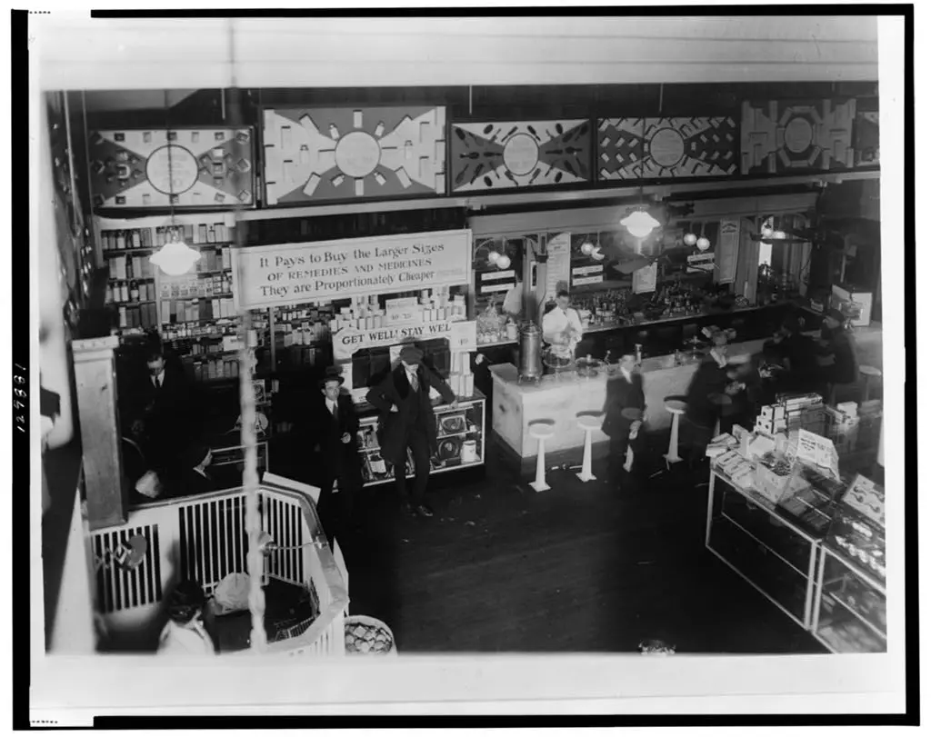 Aerial perspective of the interior of People's Drug Store at 7th and E Streets, Washington, D.C., highlighting the prominent soda fountain counter surrounded by chairs.