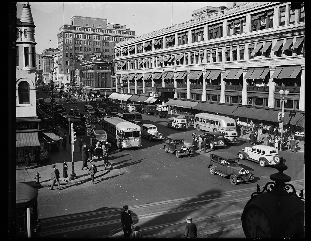 Capital Transit buses and 1930s automobiles on a crowded downtown Washington DC street in October 1935, with streetcar tracks visible in the pavement
