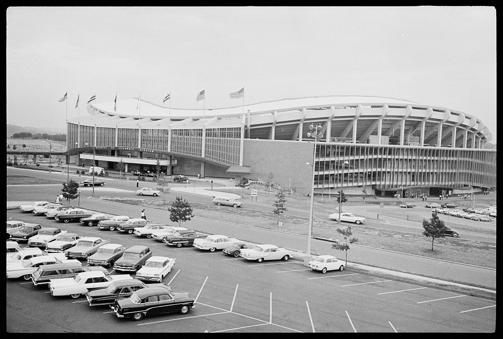 1960s-era cars parked outside the low, curved exterior of D.C. Stadium.