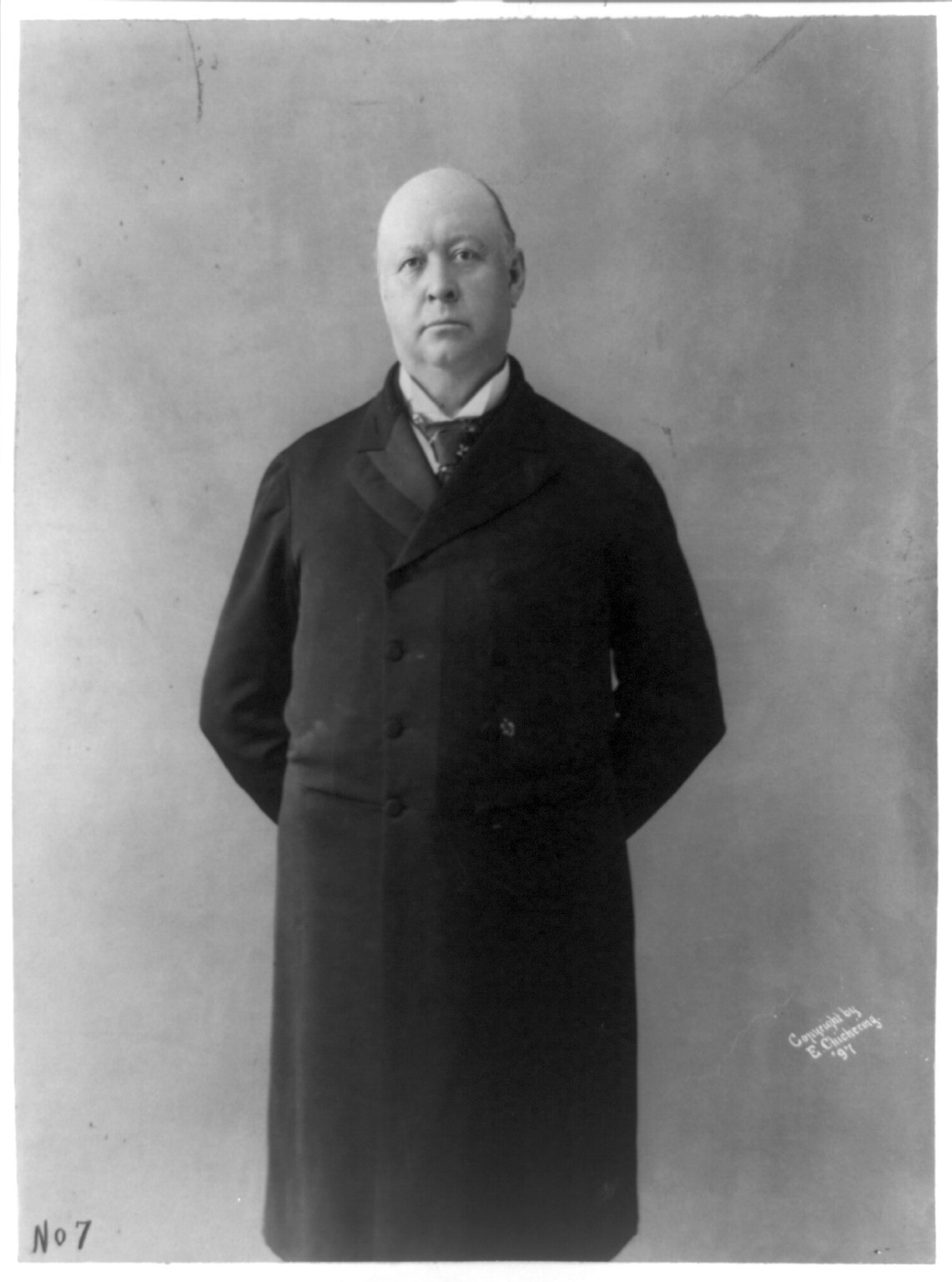Thomas Brackett Reed standing in a long overcoat, full-figure photograph showing his imposing size, c. 1897