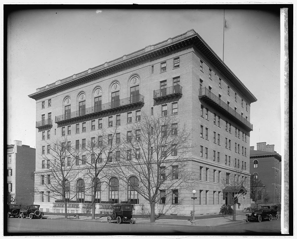 Six-story neoclassical 1912 Army and Navy Club building seen from the corner, with early automobiles parked along the curb