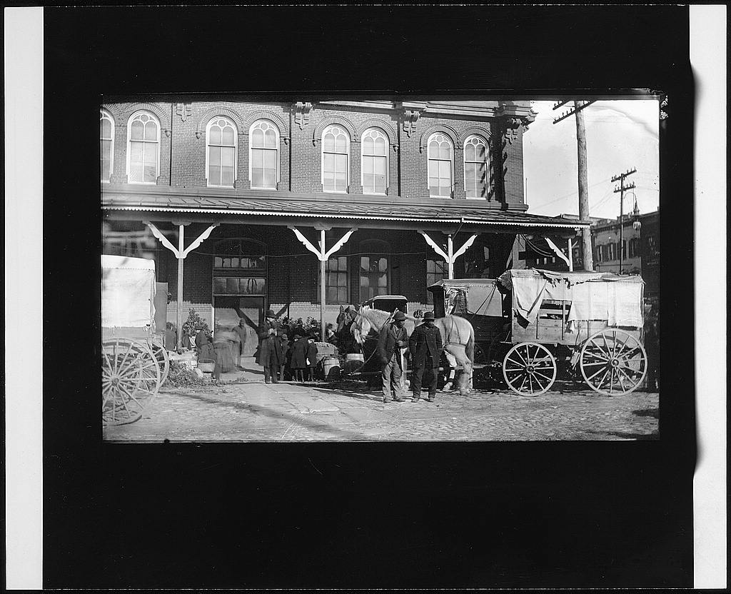 Horse-drawn wagons lined up in front of Center Market in Washington D.C., circa 1890 to 1910.