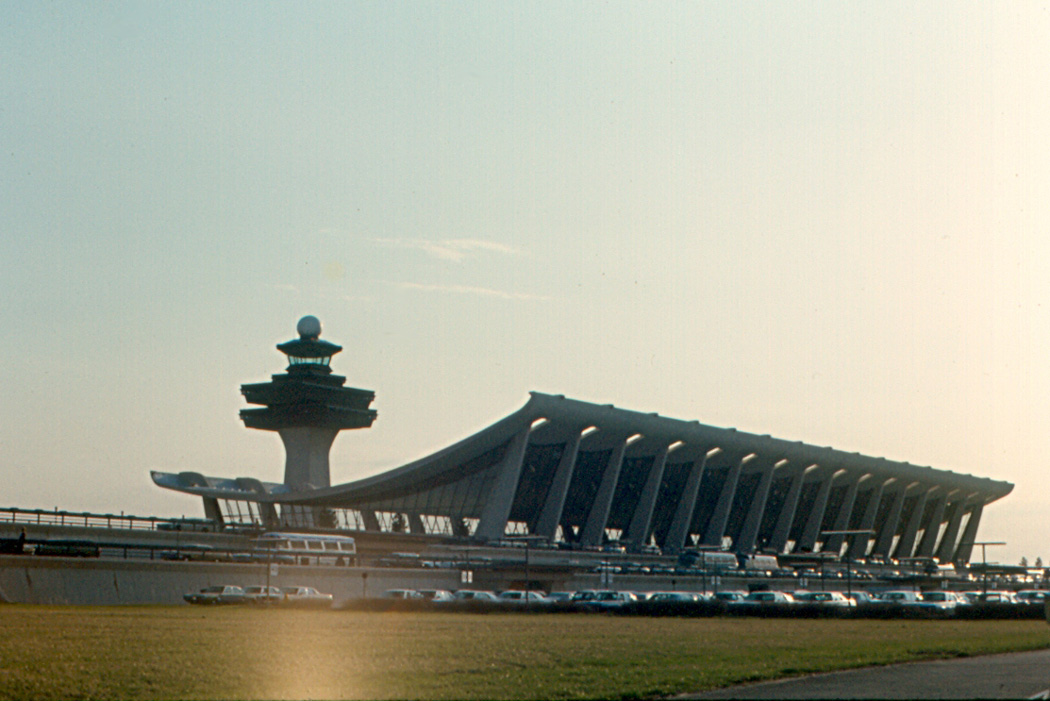 The main terminal at Dulles International Airport photographed in 1970, showing the original Saarinen building before the 1990s extension, with the distinctive sweeping concrete roof and angled support columns.