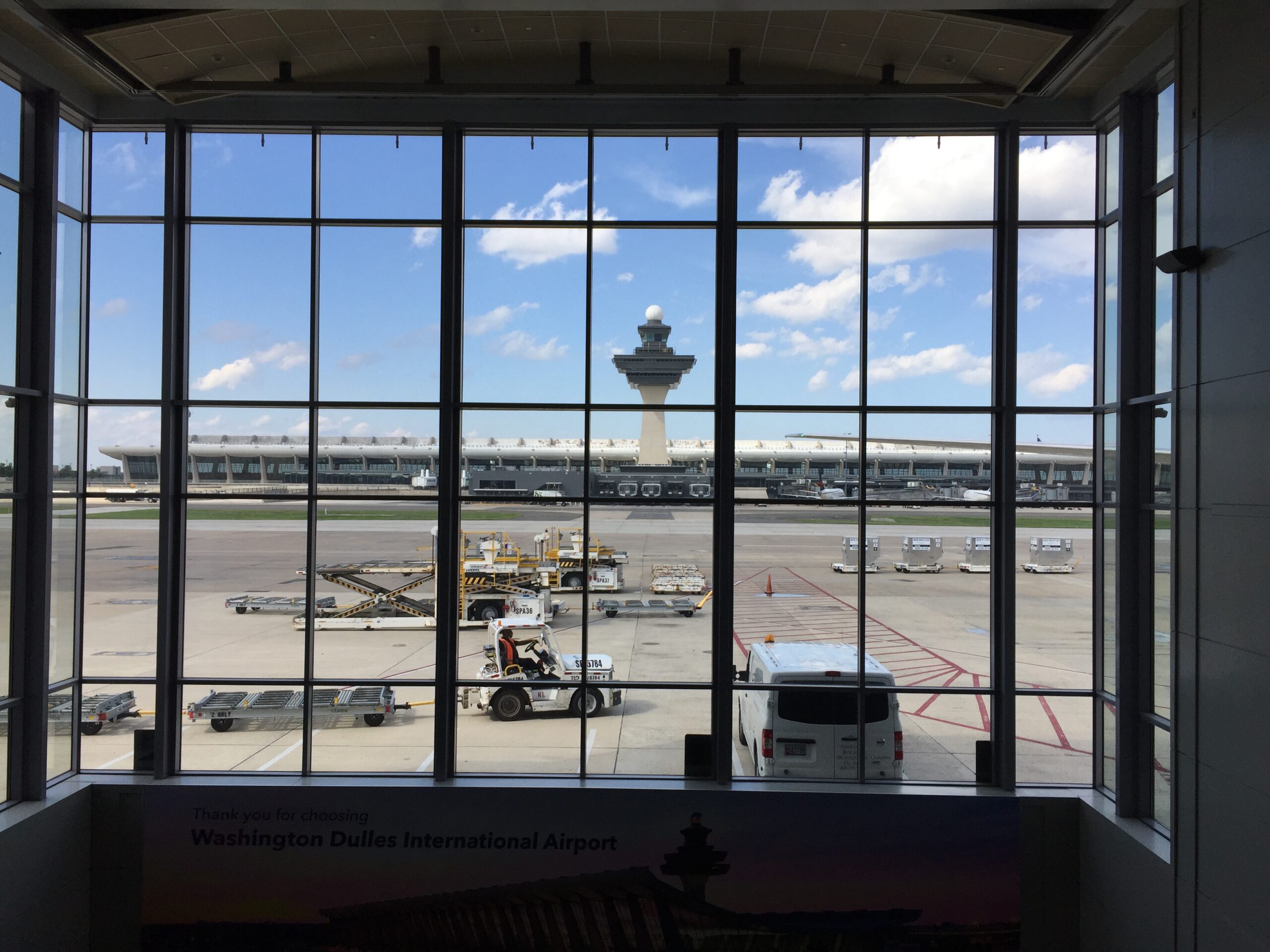 Washington Dulles International Airport main terminal photographed from the parking structure in 2021, showing the full sweep of the Saarinen roofline against a clear sky.