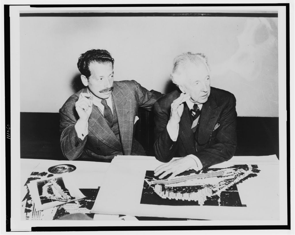 Frank Lloyd Wright seated at a table with developer Roy S. Thurman, Crystal Heights drawings between them, 1940