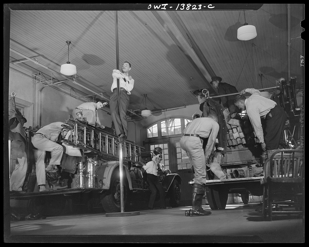 Black firefighters of Engine Company No. 4 pulling on boots and coats at the alarm, 1943