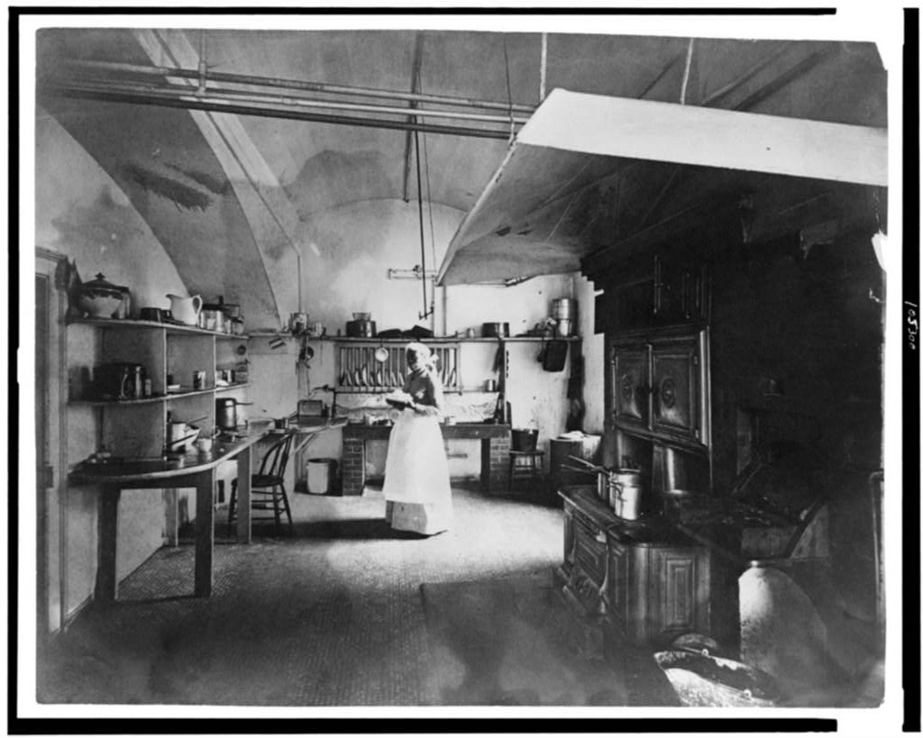 White House kitchen photographed by Frances Benjamin Johnston in 1891, with a large cast iron range, copper pots on shelves, and the basement cooking room Caroline Harrison inherited.