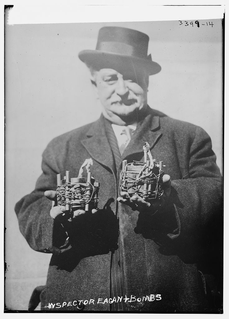 Bomb squad inspector Owen Egan holding two seized bombs in 1915