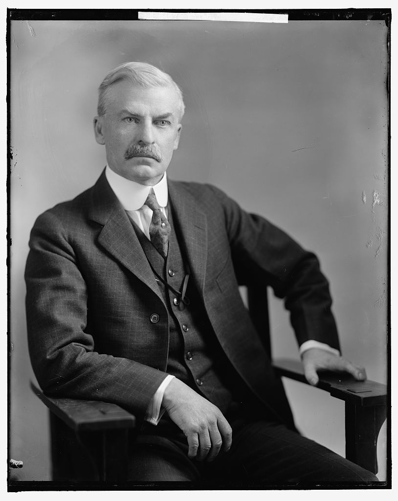 A three-quarter studio portrait of Senator Thomas J. Walsh of Montana, seated in a three-piece suit, with a thick mustache.
