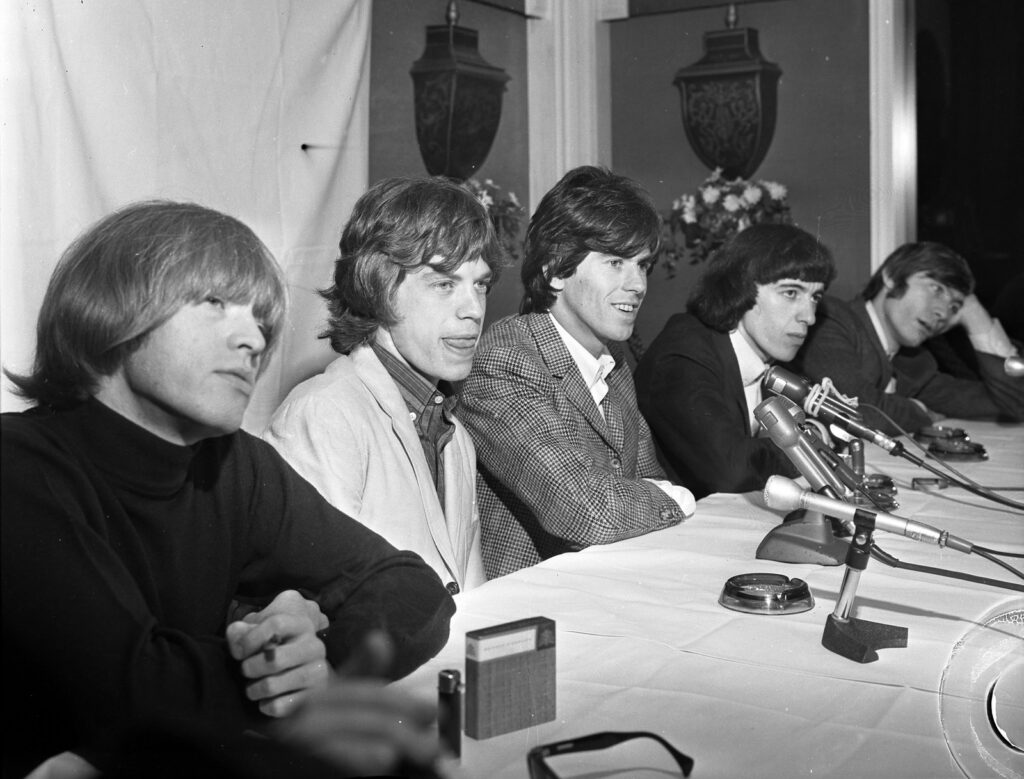 The Rolling Stones at a Beverly Hills press conference on their 1965 American tour. From left: Brian Jones in a black turtleneck, Mick Jagger, Keith Richards, Bill Wyman, and Charlie Watts.