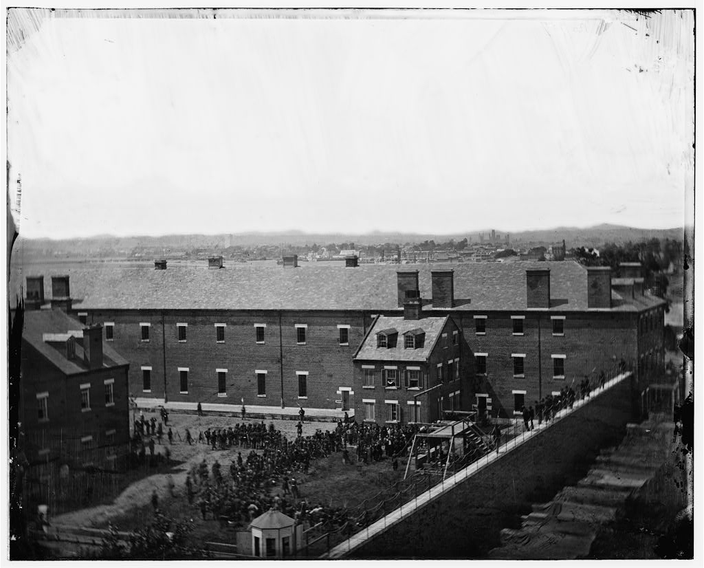 Black-and-white photograph from the roof of the Washington Arsenal on July 7, 1865, showing the scaffold and crowd in the yard during the execution of the Lincoln conspirators.