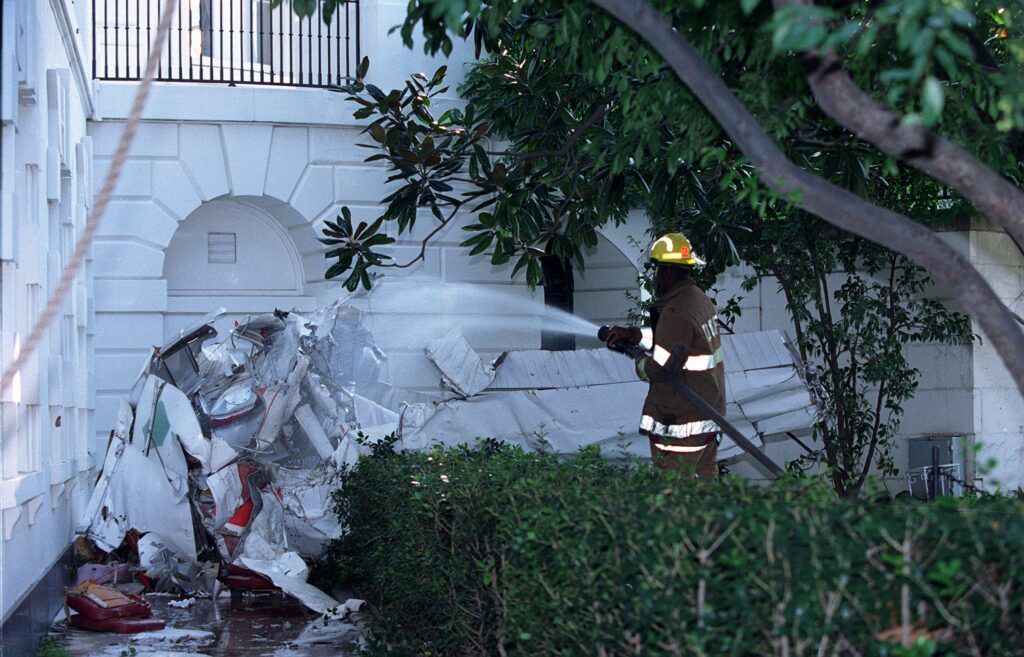 A firefighter hoses down the Cessna wreckage at the south wall of the White House, September 12, 1994