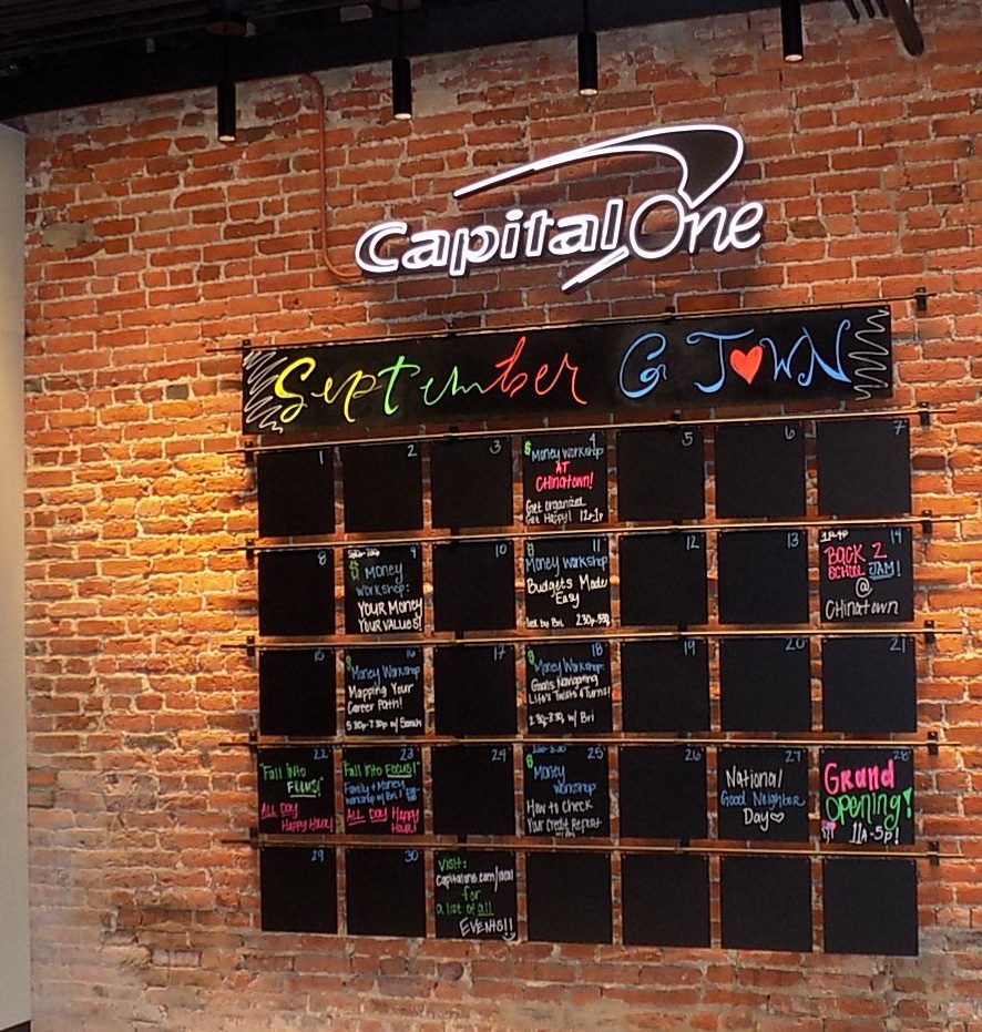 Capital One Cafe Georgetown exposed brick wall with hand-lettered September community events calendar marking the Grand Opening