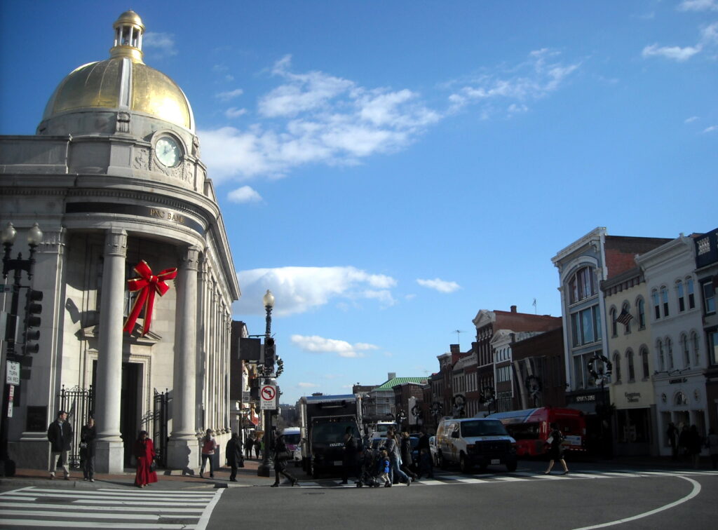 The intersection of M Street and Wisconsin Avenue in Georgetown, facing east, with the Riggs Bank gold dome on the left and the Nathans building on the right corner