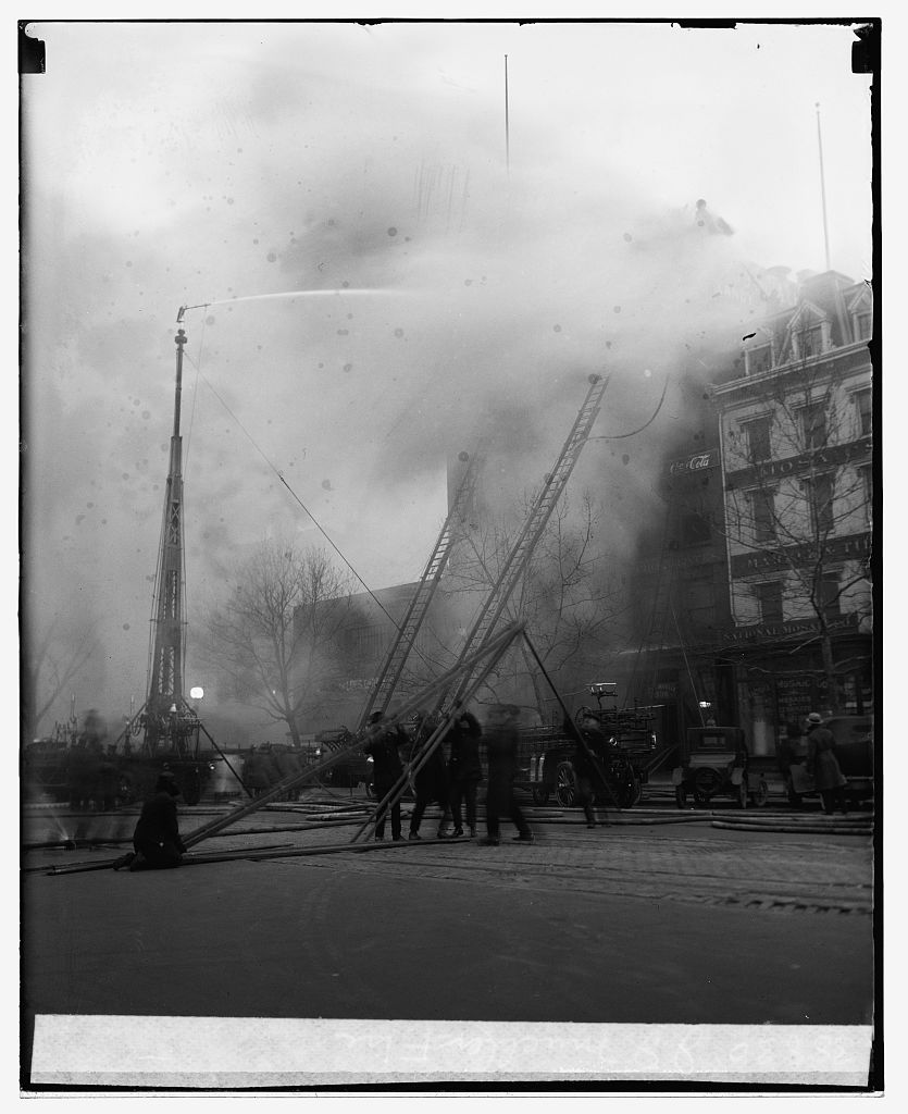 Firemen and the water tower fight the five-alarm fire at the George J. Mueller Candy Co., 336 Pennsylvania Avenue NW, December 28, 1925, with the National Mosaic Co. store at right