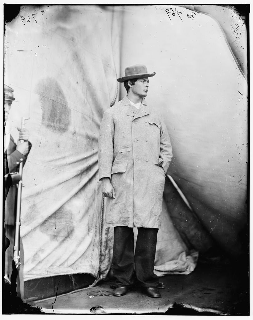 Lewis Powell standing in overcoat and hat on the deck of the USS Saugus at the Washington Navy Yard, April 1865
