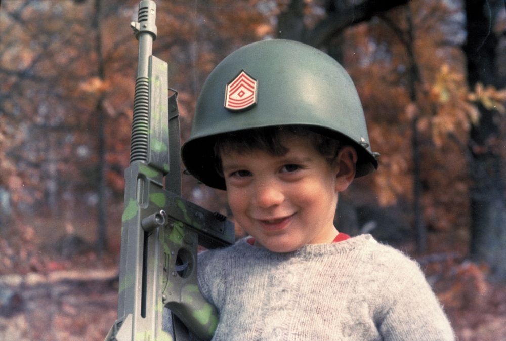 John F. Kennedy Jr. wearing a helmet and holding a toy sub-machine gun at Wexford in Atoka, Virginia, November 10, 1963