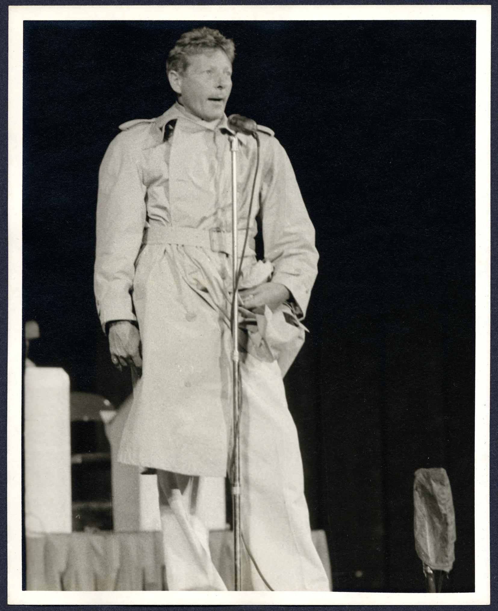 Danny Kaye performs in a trench coat on the Carter Barron Amphitheater stage, 1956