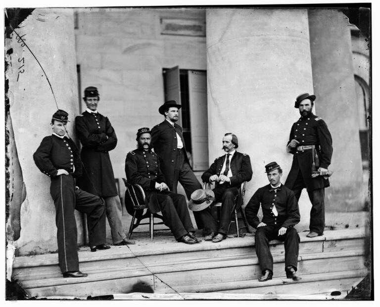 Union officers in uniform, some seated, gathered between the massive columns of the Arlington House portico