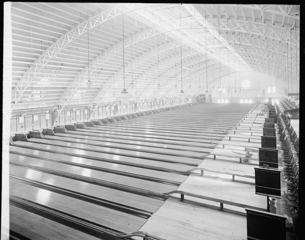 Long rows of bowling lanes stretching under the arched iron roof trusses of Convention Hall