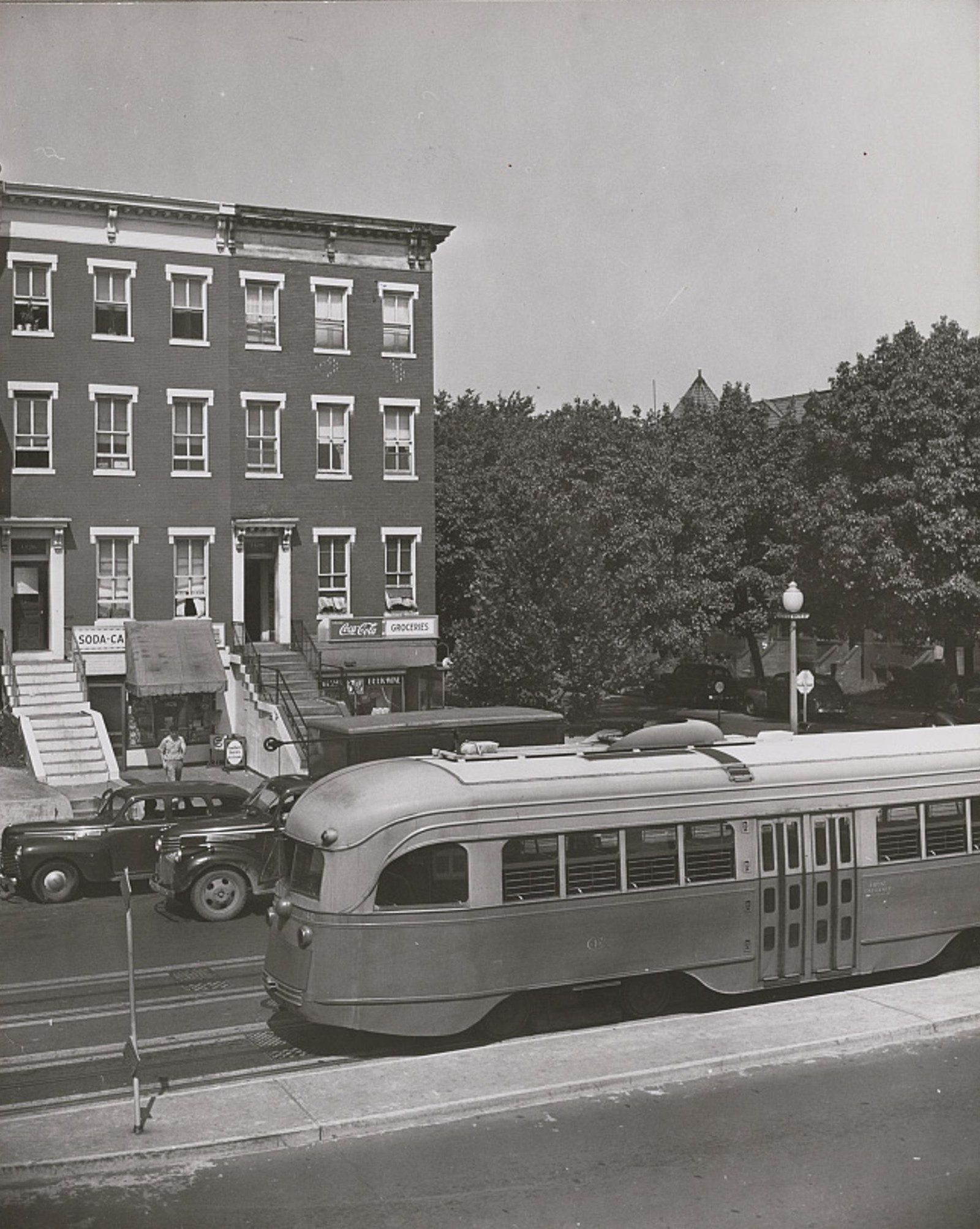 Corner stores at 1426 and 1428 11th Street NW with a streetcar passing, 1942