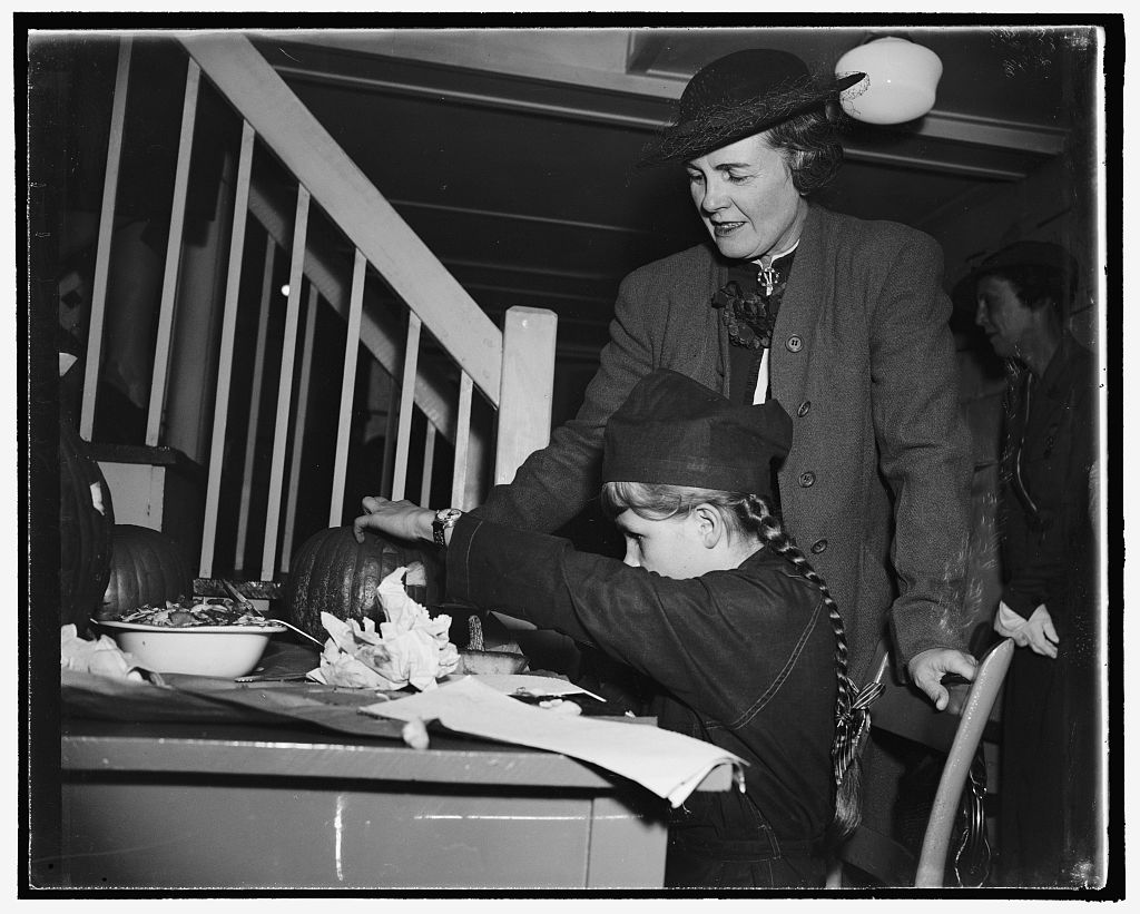 Mrs. Henry A. Wallace shows a Girl Scout how to cut out a pumpkin, Washington, 1938