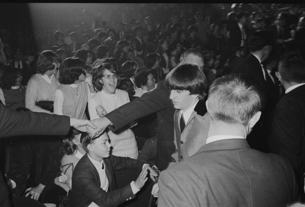 A packed crowd of teenagers inside Washington Coliseum, some laughing and reaching out
