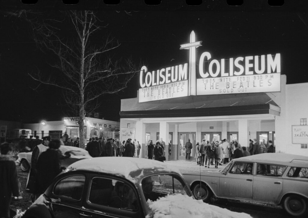 The lit Washington Coliseum marquee at night reading Tues Nite Feb 11 830 PM The Beatles Sold Out, with snow-covered cars in front