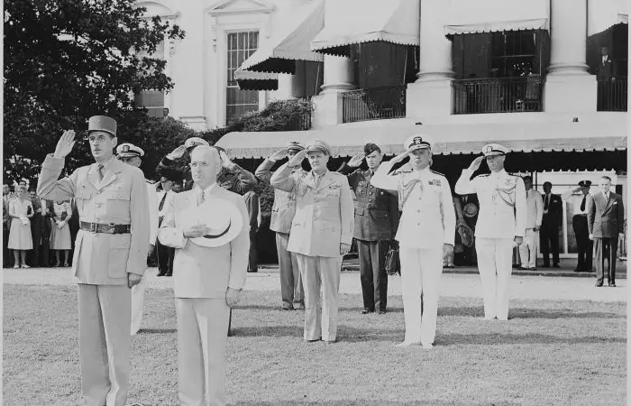 Photograph of President Truman and French President Charles de Gaulle, during welcoming ceremonies on the White House lawn, with officers saluting in the background. (August 22nd, 1945)